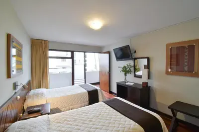 a hotel room with two beds and a television at Hotel Señorial in Lima