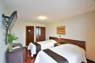 a hotel room with two beds and a flat screen tv at Hotel Señorial in Lima