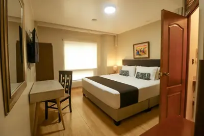 a bedroom with a bed and a table and a window at Epiqus Hotel in Lima