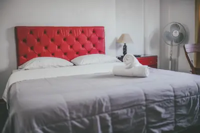 a bedroom with a large bed with a red headboard at Hotel Excalibur in Lima