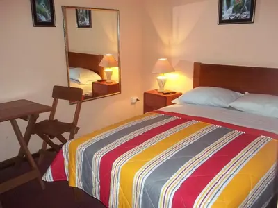 a bedroom with a bed and a desk and a mirror at Hotel Excalibur in Lima
