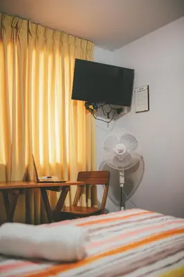a bedroom with a bed and a desk and a fan at Hotel Excalibur in Lima