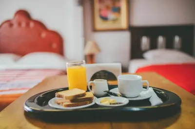 a tray with toast and orange juice and a plate of food at Hotel Excalibur in Lima