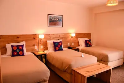 a hotel room with two beds and a table at Cooper Hotel Boutique in Cusco