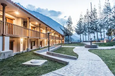a walkway next to a building with mountains in the background at Del Pilar Ollantaytambo in Ollantaytambo