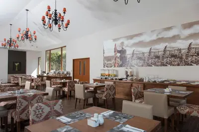 a restaurant with tables and chairs and a painting on the wall at Del Pilar Ollantaytambo in Ollantaytambo