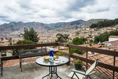 a table and chairs on a balcony overlooking a city at Samay Wasi Hostel in Cusco