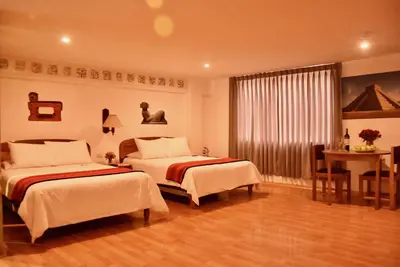 a hotel room with two beds and a table at Los Aticos B&B with Coworking in Cusco