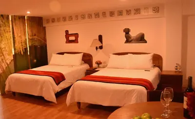 a hotel room with two beds and a table at Los Aticos B&B with Coworking in Cusco