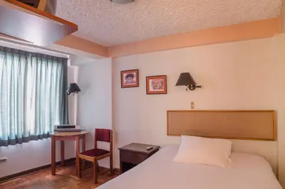 a bedroom with a bed and a table and a chair at Los Aticos B&B with Coworking in Cusco
