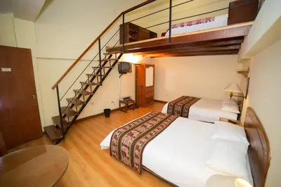 a bedroom with two beds and a staircase at Los Aticos B&B with Coworking in Cusco