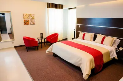 a hotel room with a bed and two red chairs at Verona Hotel Baños Turcos in Lima