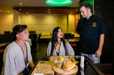 a group of people sitting around a table with a hamburger at Verona Hotel Baños Turcos in Lima