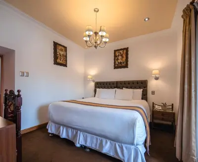 a bedroom with a large white bed with a chandelier at Hotel Rojas Inn in Cusco