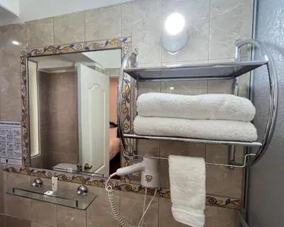 a bathroom with a rack of towels and a mirror at Hotel Rojas Inn in Cusco