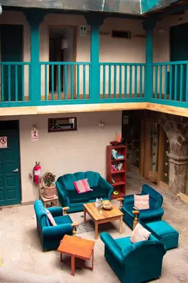 a living room with blue couches and tables in front of a building at Nao Victoria Hostel in Cusco