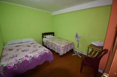 a bedroom with two beds and a table with a fan at El Viajero Aeropuerto in Lima