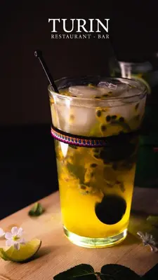 a drink on a wooden table with a lemon at Hotel Turin in Tarma