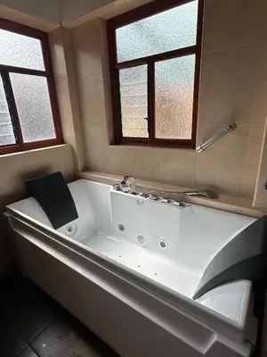 a white bath tub in a bathroom with two windows at Hotel Mabey Urubamba in Urubamba