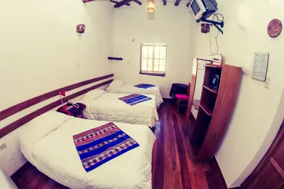 a room with two beds and a window at Hostal El Grial in Cusco