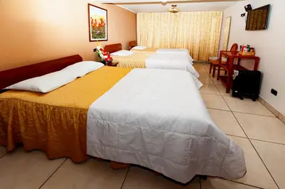 a hotel room with two beds and a table at Hotel Sol del Oriente Cusco in Cusco