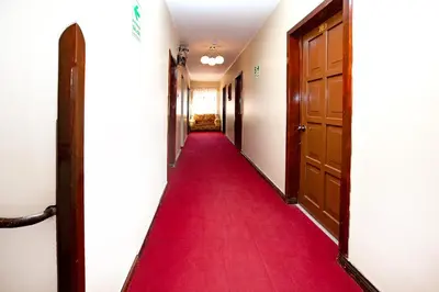 a hallway with a red carpet and doors at Hotel Sol del Oriente Cusco in Cusco