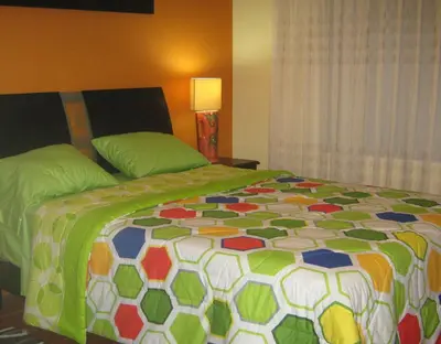 a bedroom with a bed with a colorful quilt at apartamentos Los cedros in Lima