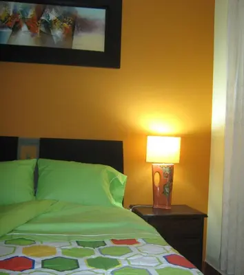 a bedroom with a bed and a lamp on a table at apartamentos Los cedros in Lima