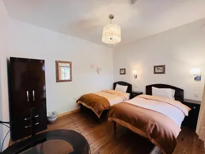 a bedroom with two beds and a chandelier at Hostal Qorichaska in Cusco