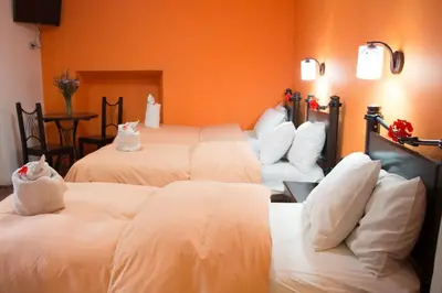 a hotel room with three beds with white pillows at Hostal Qorichaska in Cusco