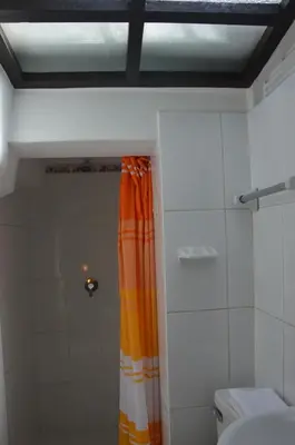 a bathroom with a shower with an orange shower curtain at Hostal Wasichay in Cusco