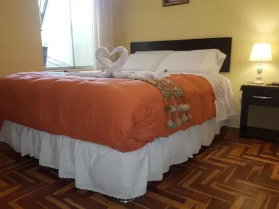 a bedroom with a large bed with an orange blanket at Hostal Wasichay in Cusco