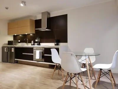 a kitchen with a glass table and white chairs at Lima Walking Apartments - Central Miraflores in Lima