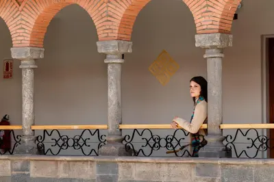 a woman sitting on a fence in a building at Hotel Hacienda Sonqori Centro Histórico in Cusco