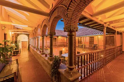 an empty building with a balcony with tables and chairs at Hotel Hacienda Sonqori Centro Histórico in Cusco