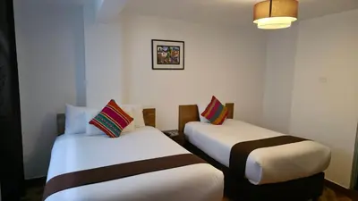 two beds in a room with white walls at Mapi Garden's Machupicchu in Machu Picchu