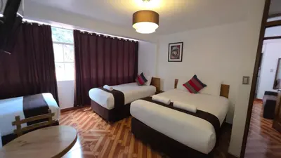a hotel room with two beds and a table at Mapi Garden's Machupicchu in Machu Picchu