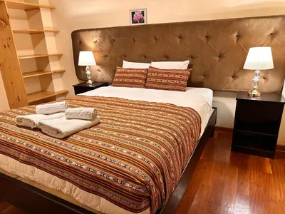 a bedroom with a large bed with two lamps at Hotel Las Quenas in Cusco
