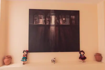 a painting on a wall with three figurines on a shelf at Hotel Las Quenas in Cusco