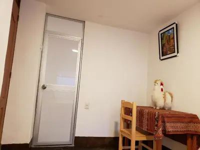 a chicken sitting on a chair next to a glass door at Feliz Vista Casa-Hospedaje in Cusco
