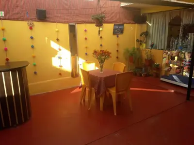 a table and chairs in a room with a yellow wall at Feliz Vista Casa-Hospedaje in Cusco