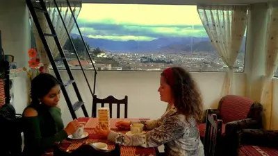 two women sitting at a table in a room with a window at Feliz Vista Casa-Hospedaje in Cusco