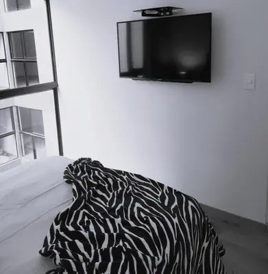 a black and white pillow sitting on a bed with a tv at LA POSADA DE GUILLE LUXURY 1 HABITACION - Surco in Lima