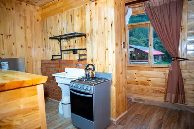 a kitchen with a stove and a sink in a cabin at Fundo Hassinger in Oxapampa