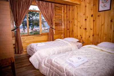 two beds in a room with wooden walls at Fundo Hassinger in Oxapampa