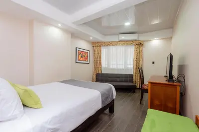 a bedroom with a bed and a television and a couch at La Luna Inn in Lima