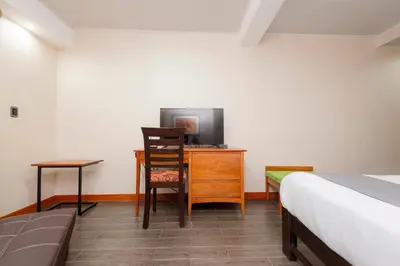 a bedroom with a bed and a desk with a television at La Luna Inn in Lima