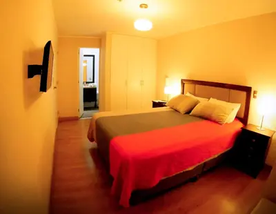 a bedroom with a large bed with a red blanket at MIRAFLORES LUXURY PLACE POOL GYM 2BD in Lima
