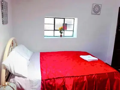 a red and white bed in a room with a window at Cuzco Central Hostel in Cusco