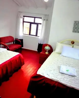 a bedroom with two beds and a chair and a window at Cuzco Central Hostel in Cusco